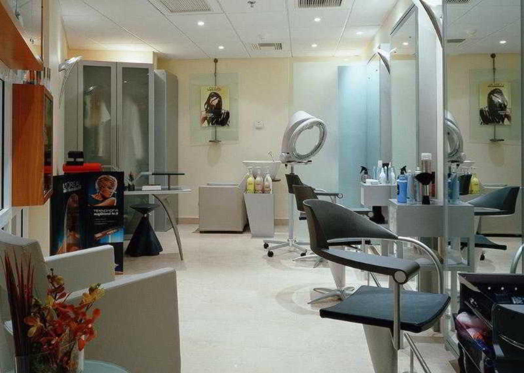 فندق سوفيتِل أثينا إيربورت Spáta المظهر الخارجي الصورة The photo depicts a modern hair salon interior. There are several styling stations equipped with mirrors and chairs, allowing customers to sit while their hair is being done. The walls are light-colored, creating a bright and open atmosphere. In the 