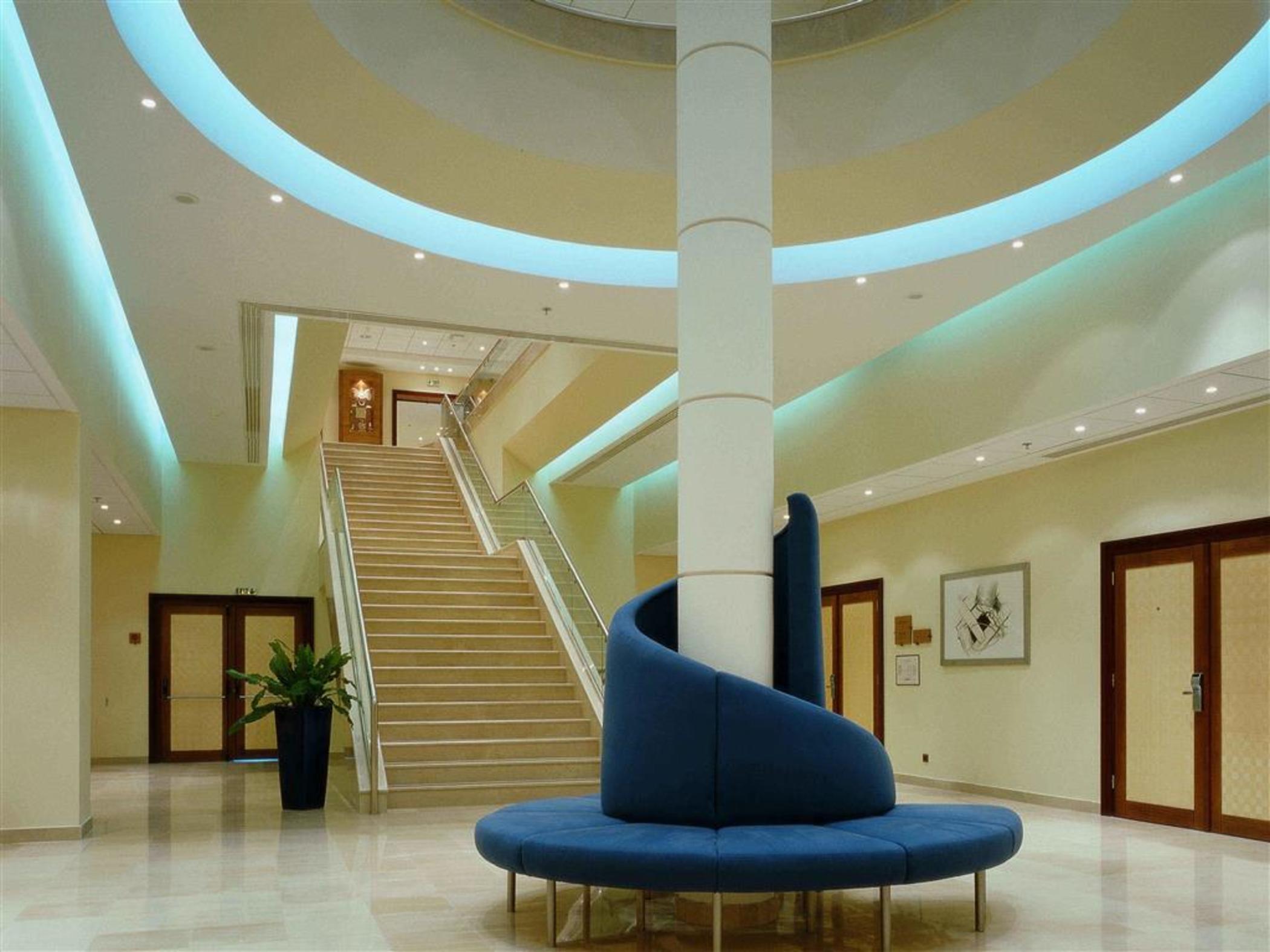 فندق سوفيتِل أثينا إيربورت Spáta المظهر الداخلي الصورة The photo shows a modern lobby area with an elegant design. There is a large, spiraled seating fixture in blue, which is situated in the center. Surrounding this seating area, the floor is made of polished tiles that reflect light. 

Behind the seati
