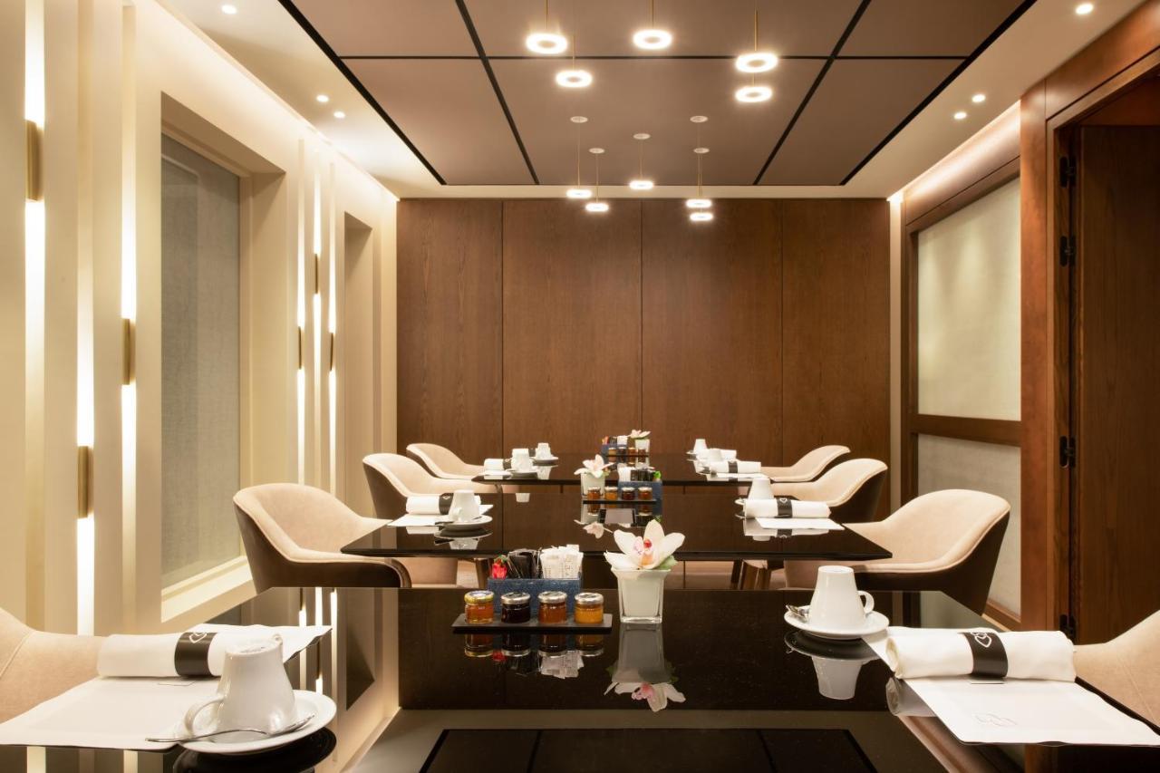 فندق سوفيتِل أثينا إيربورت Spáta المظهر الخارجي الصورة The photo shows a modern and elegantly designed dining or meeting room. It features a sleek, dark table surrounded by several light-colored chairs. The walls are adorned with warm wood paneling, and the ceiling has recessed lighting that adds a soft 